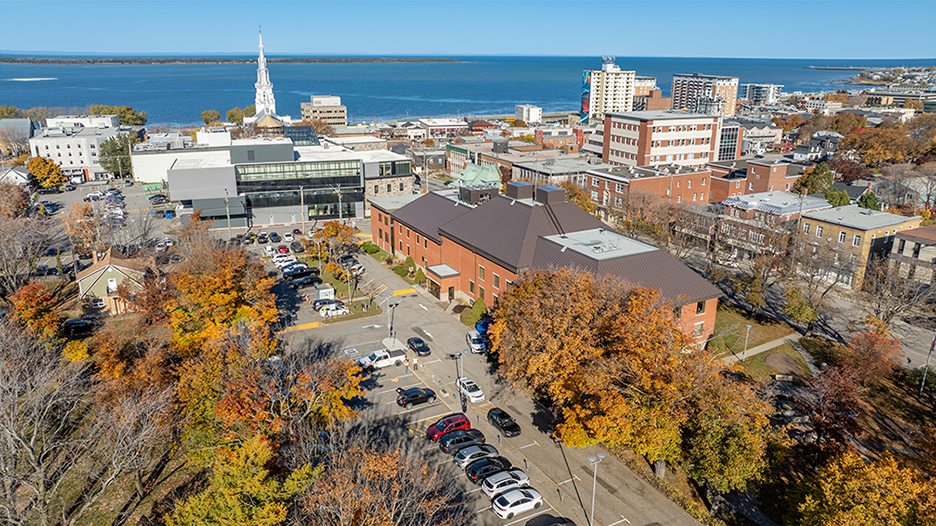 Vue aérienne par drone d’un centre-ville en bordure du fleuve, illustrant le développement urbain et institutionnel.